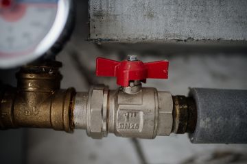 File:Close-up view of a red valve on a metallic pipe system with a pressure gauge in an industrial setting.jpg