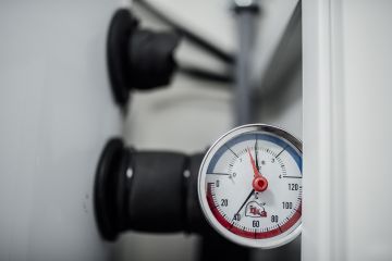 File:Pressure gauge shows measurement on equipment in a workshop setting with tools and machinery around it.jpg