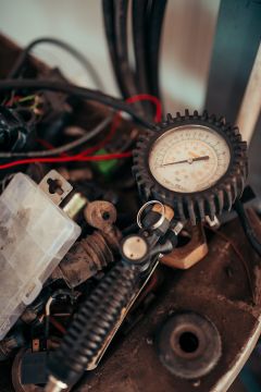 File:Old pressure gauge and tools in a workshop setting show signs of use and wear.jpg